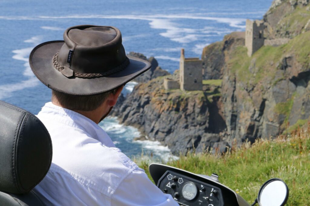 View of man in tramper looking out over the coast at National Trust Tin Coast